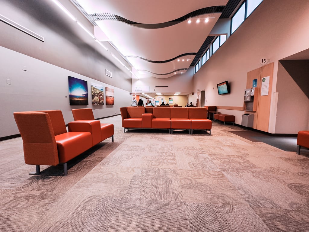 A medical clinic waiting area with high ceilings sculpted in a wave pattern and orange vinyl seats.