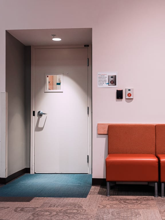 A doorway in a medical clinic. An orange/brown vinyl chair sits next to it.
